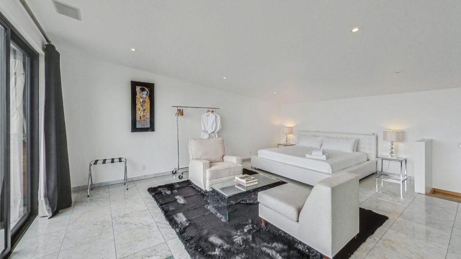 Upper level bedroom with view onto deck and city. 