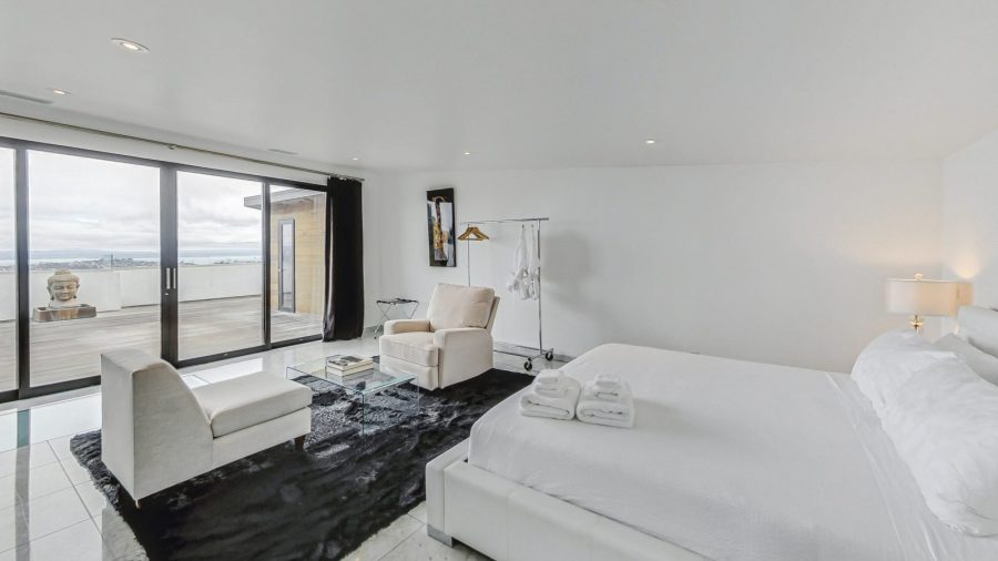 Upper level bedroom with view onto deck and city. 