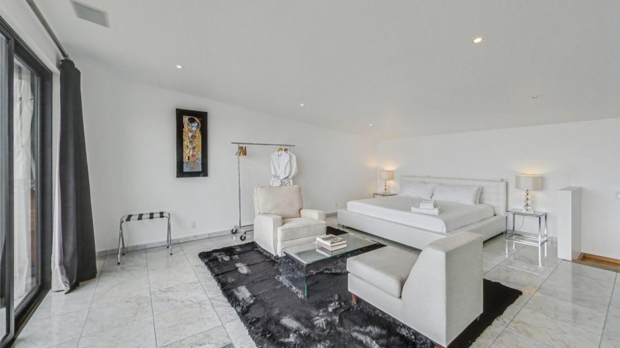 Upper level bedroom with view onto deck and city. 