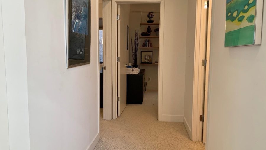 Lower level hallway to a bedroom on the left with a queen bed and a bedroom straight forward with a full bed.  There is a shared bathroom to the right.