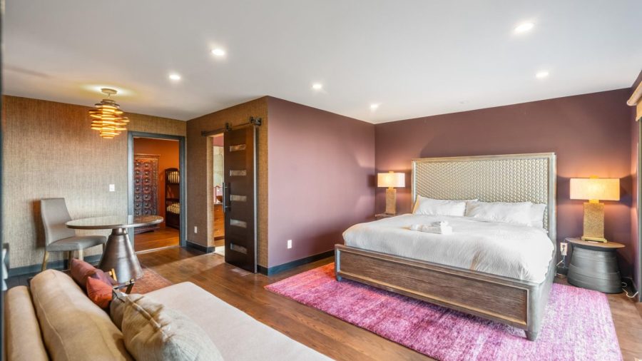 Equally spacious bedroom, to the left after descending the stairs, with en suite bathroom, access to lower deck, and access to small kids bedroom with twin-over-full bunk bed sleeping arrangement