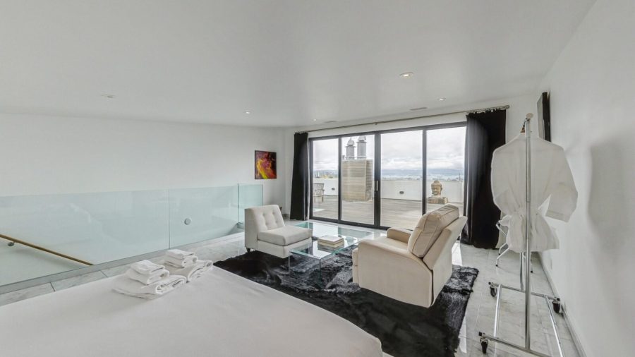 Upper level bedroom with view onto deck and city. 