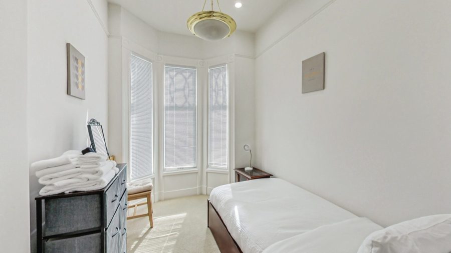 Bedroom 5 is cozy with a twin bed and a view onto Page street.