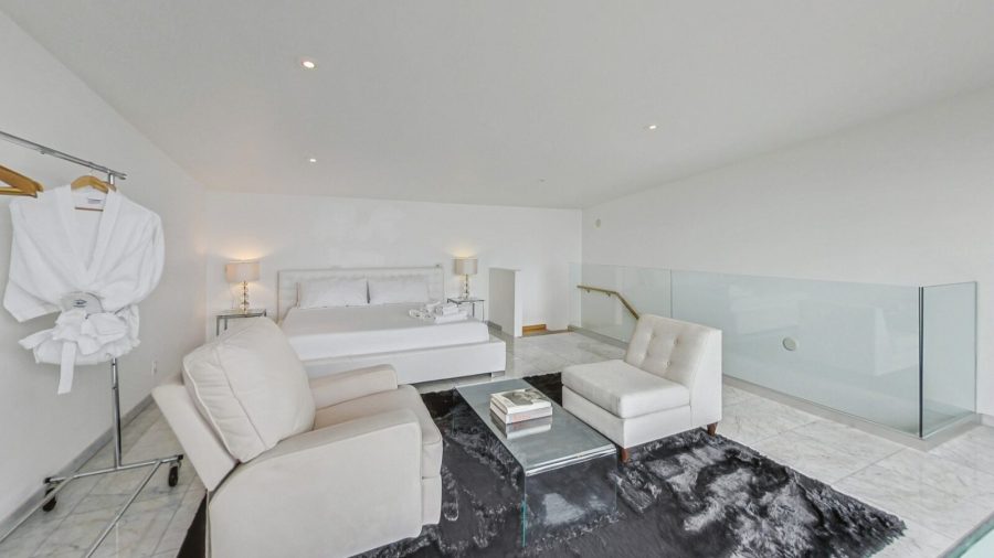 Upper level bedroom with view onto deck and city. 