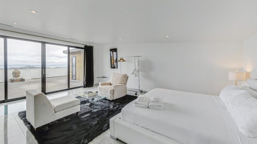 Upper level bedroom with view onto deck and city. 
