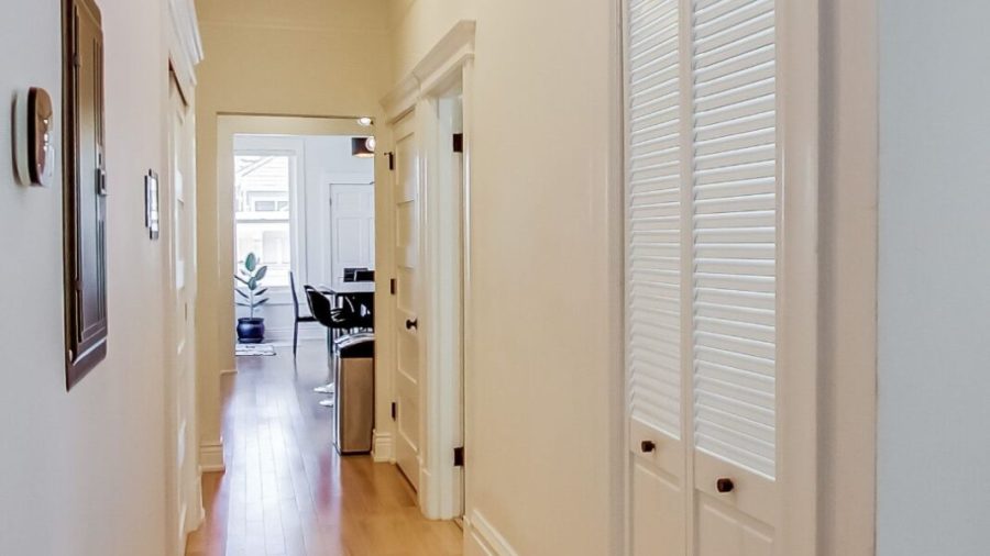 Hallway leading to kitchen, dining and back deck. Laundry is on the right behind those slatted doors.