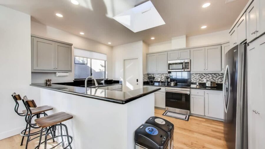 Modern, fully stocked kitchen with dishwasher, range, microwave, refrigerator, and Keurig coffee/tea maker